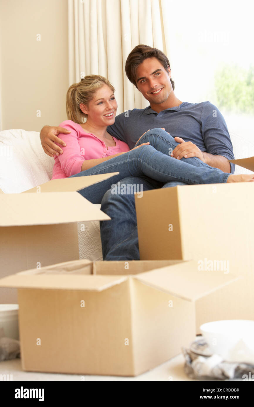 Junges Paar Umzug in neues Zuhause umgeben von Umzugskartons Stockfoto