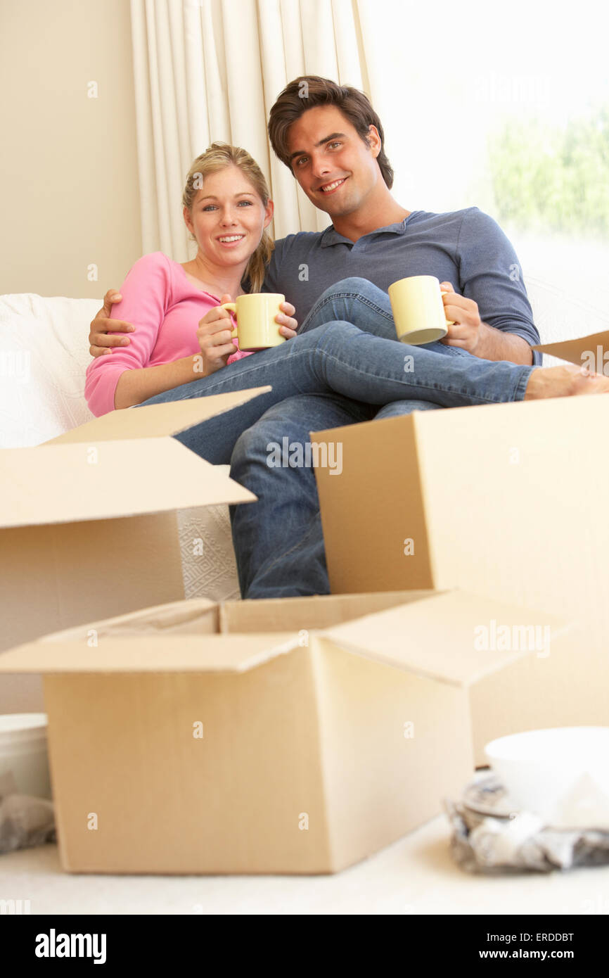 Junges Paar Umzug in neues Zuhause umgeben von Umzugskartons Stockfoto