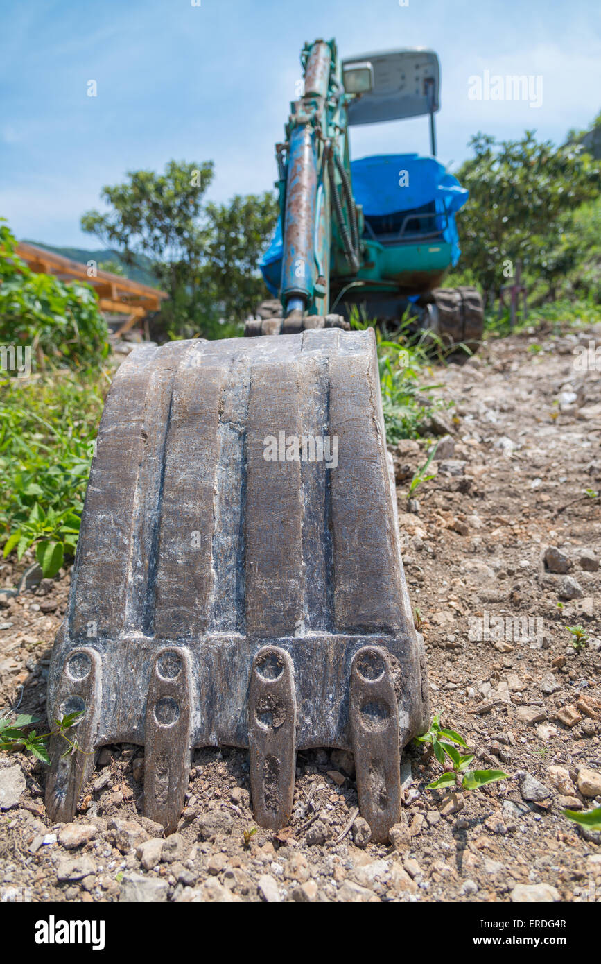 Eine Weitwinkeleinstellung eines schmutzigen Baggers in Schmutz und Felsen sitzen. Stockfoto