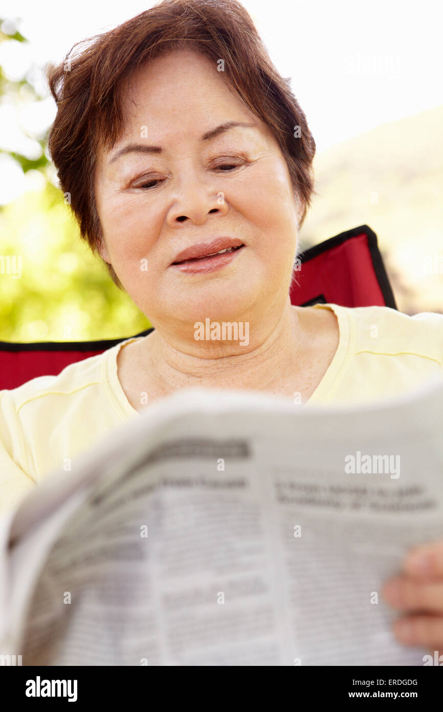 Hochrangige asiatische Frau lesen im freien Stockfoto