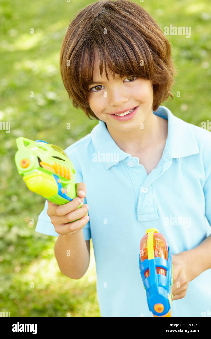 Kleiner Junge spielt mit Wasserpistolen im Park Stockfoto