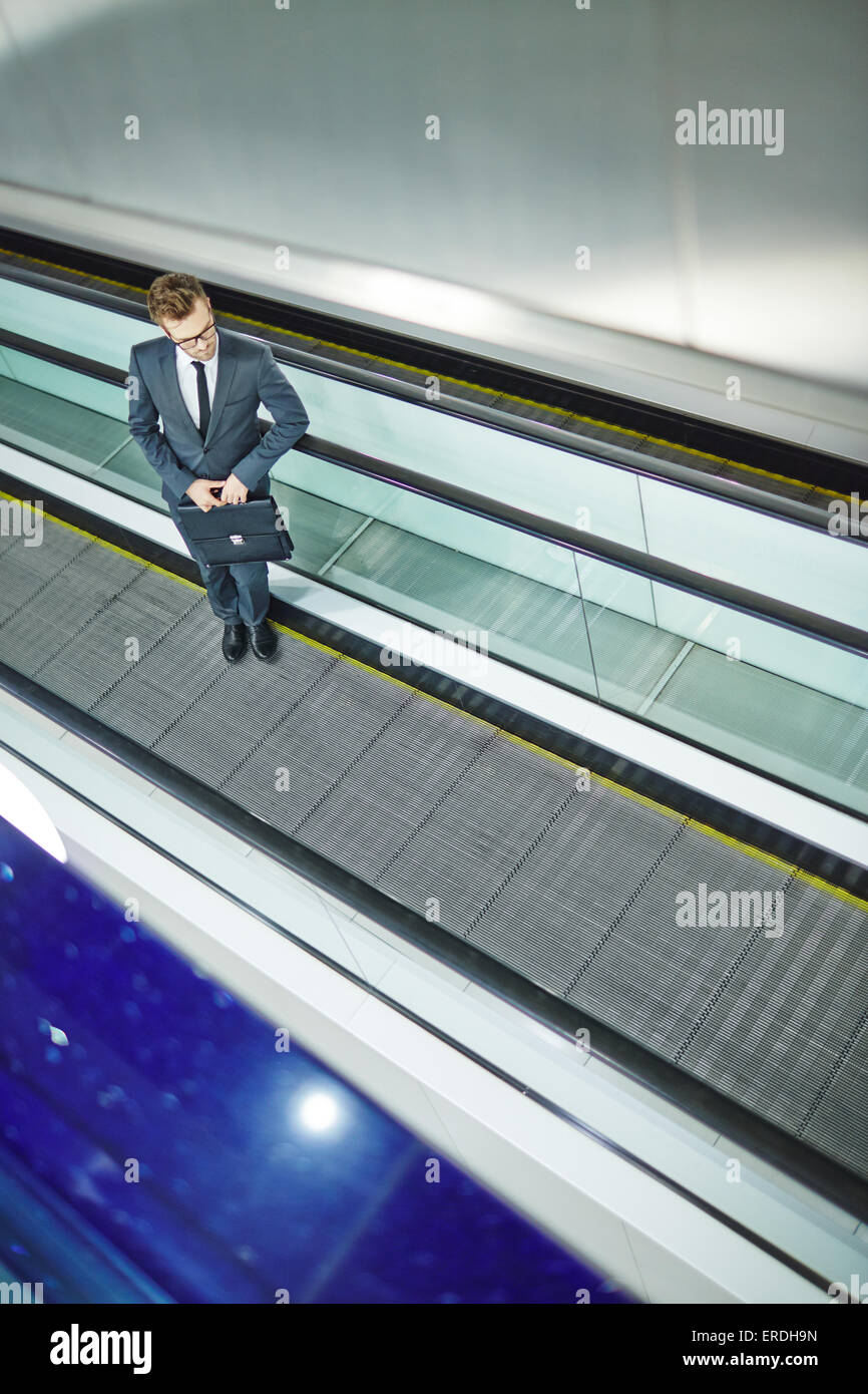 Elegante Geschäftsmann mit Aktenkoffer auf Rolltreppe nach oben bewegen Stockfoto