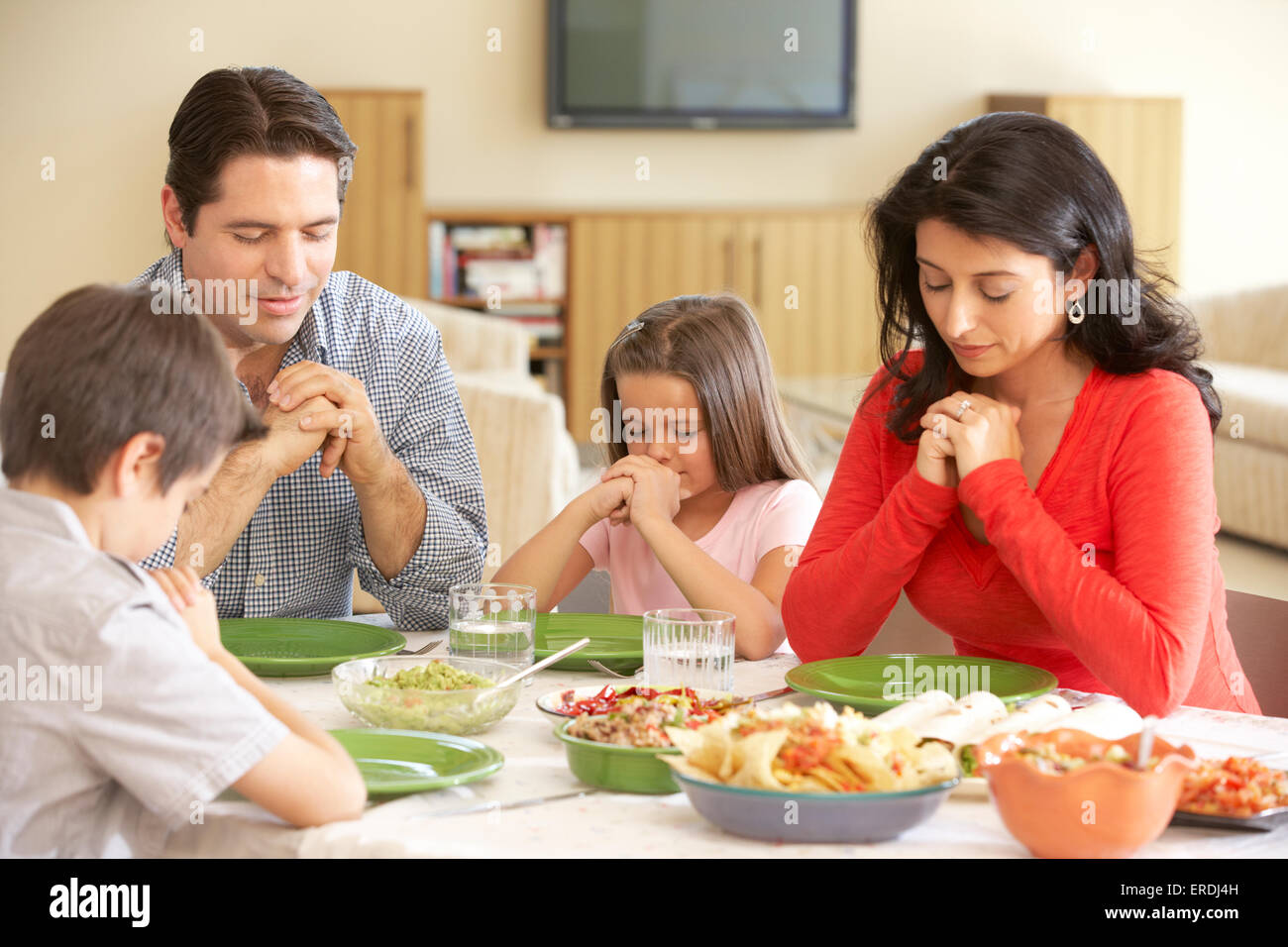 Junge spanische Familie beten vor dem Essen zu Hause Stockfoto