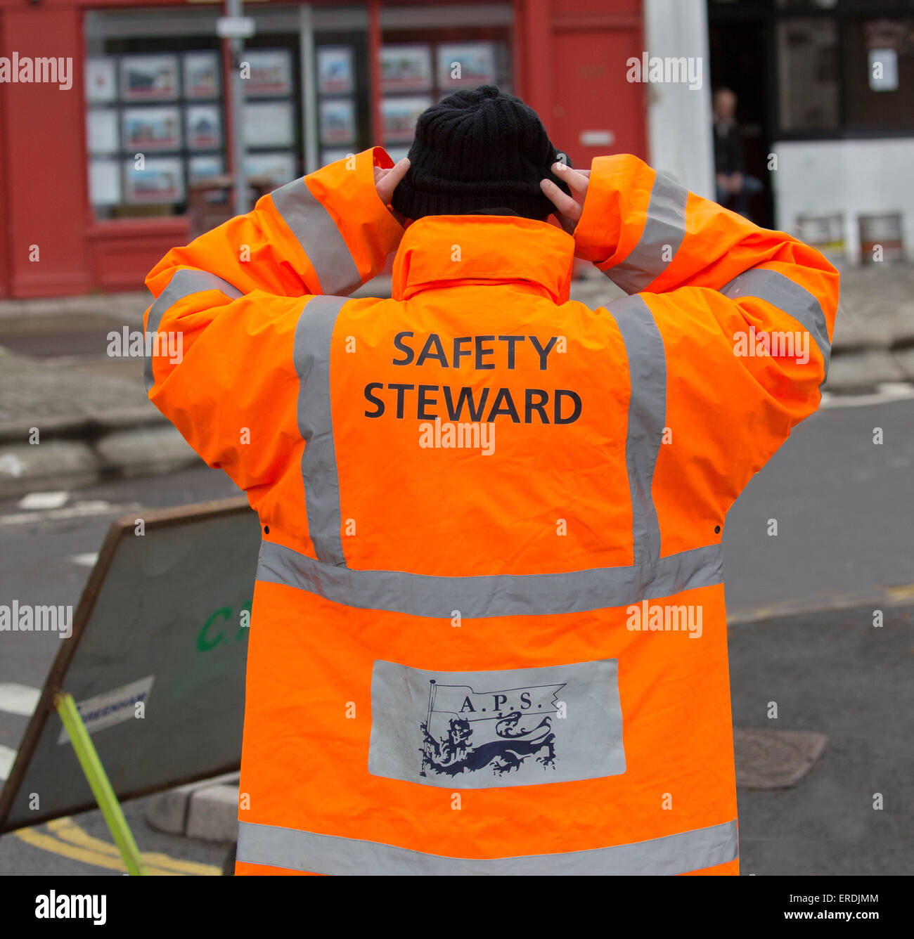 Sicherheit Steward auf einem 10 Kilometer Laufveranstaltung trägt eine orange high-Vis-Jacke Stockfoto