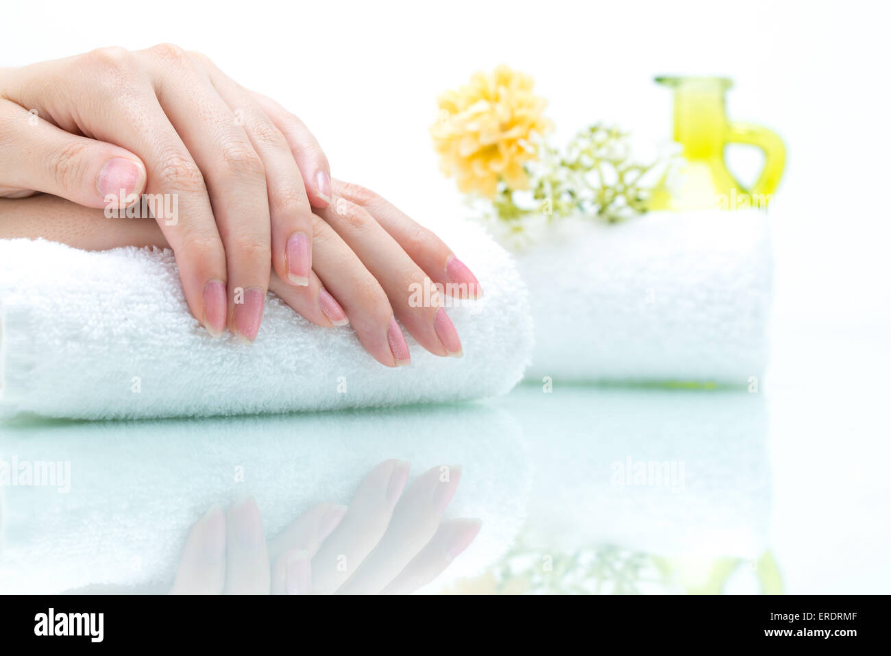 Hände am Handtuch mit grünen Flasche und Blume Stockfoto
