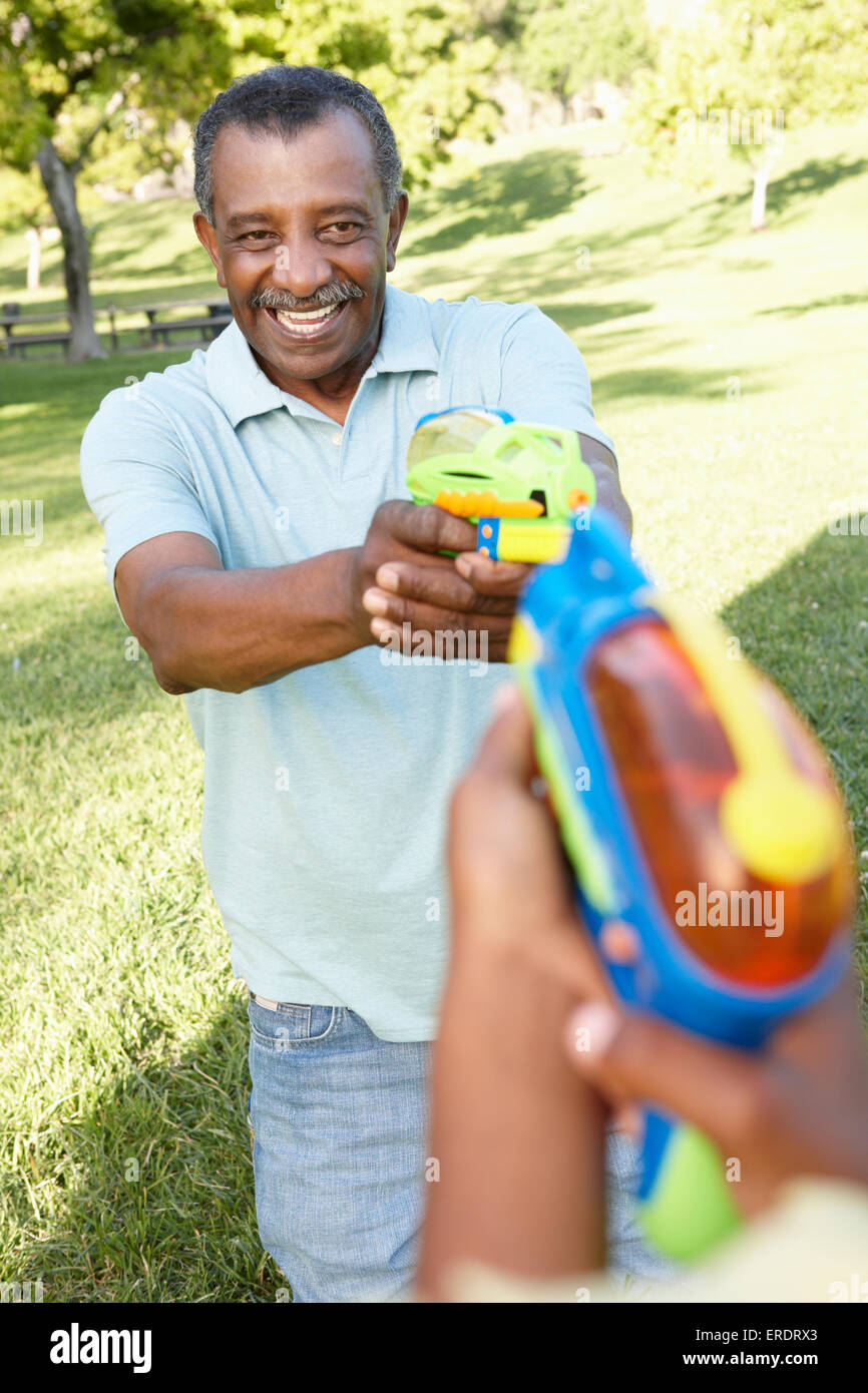 African American Großvater und Enkel spielen mit Wasserpistolen im Park Stockfoto