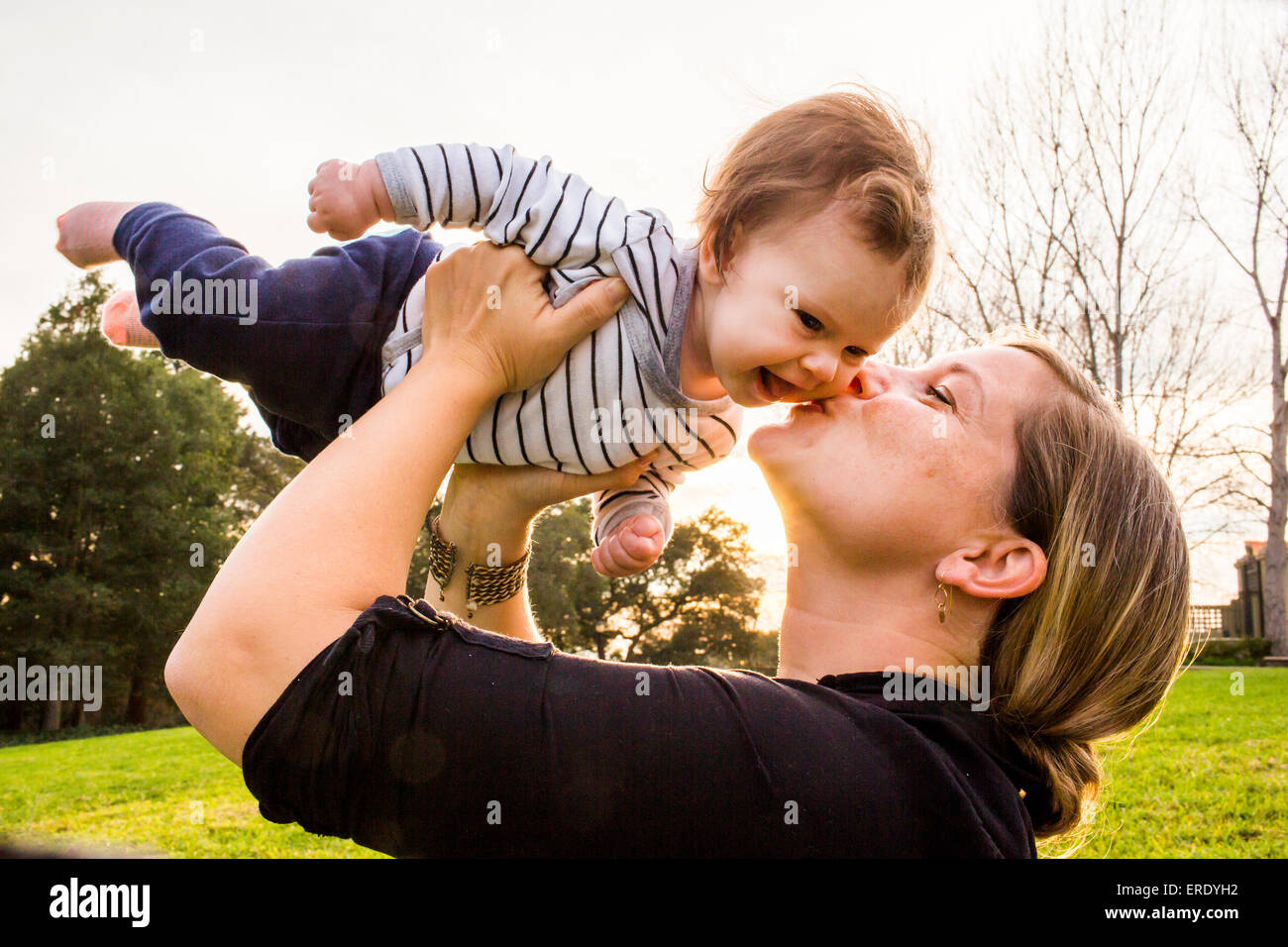 Kaukasische Mutter küssen Babymädchen im freien Stockfoto