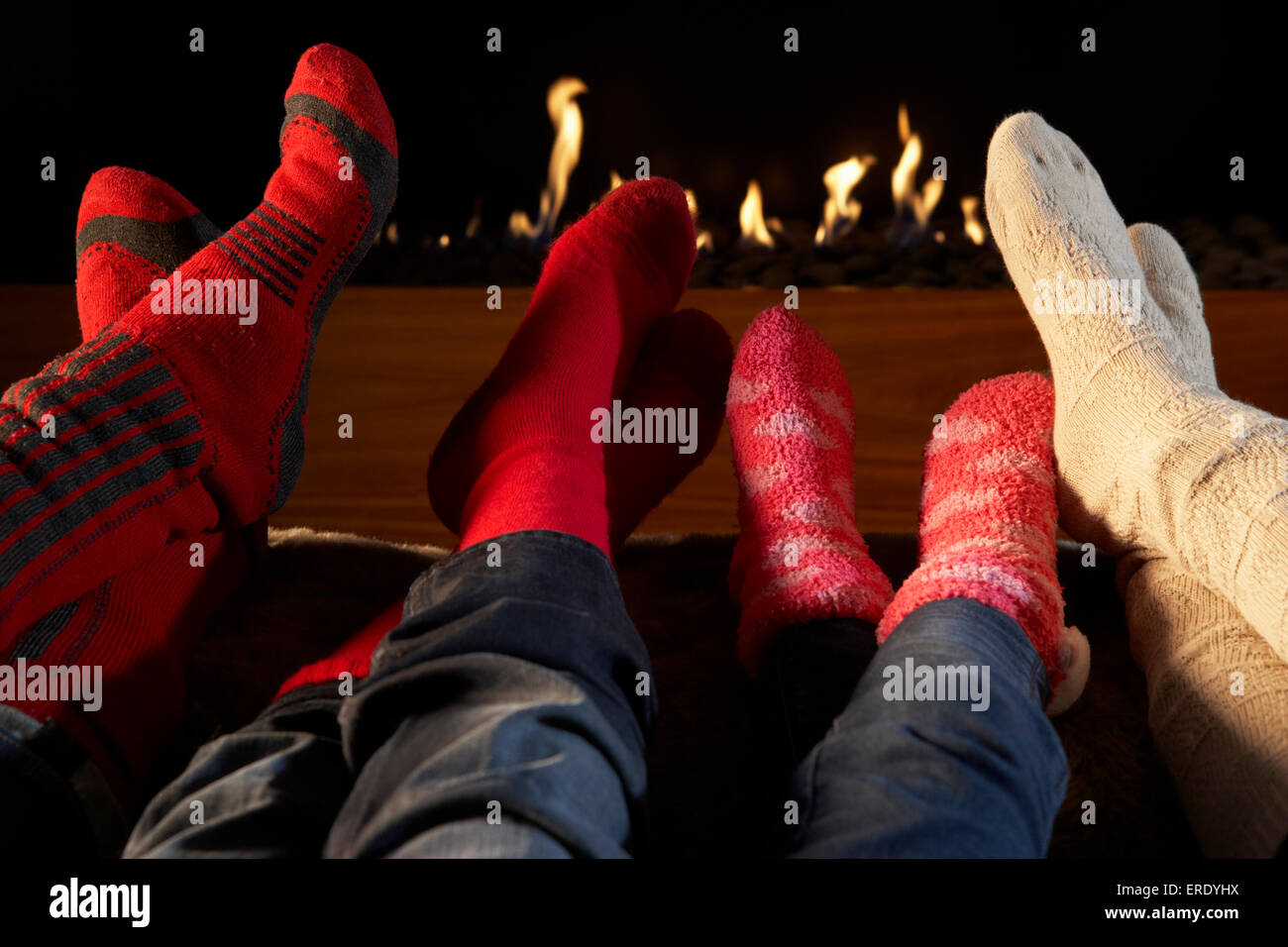 Vier Paare Füße in Socken Erwärmung durch Feuer Stockfoto