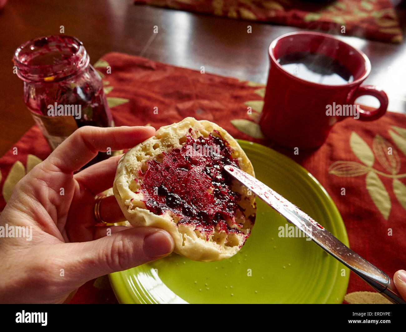 Kaukasische junge Verbreitung Marmelade auf Englisch muffin Stockfoto
