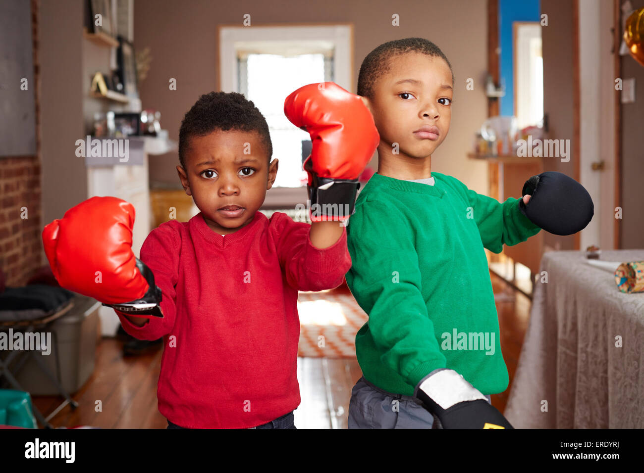 Schwarze Jungs posieren mit Boxhandschuhen im Wohnzimmer Stockfoto