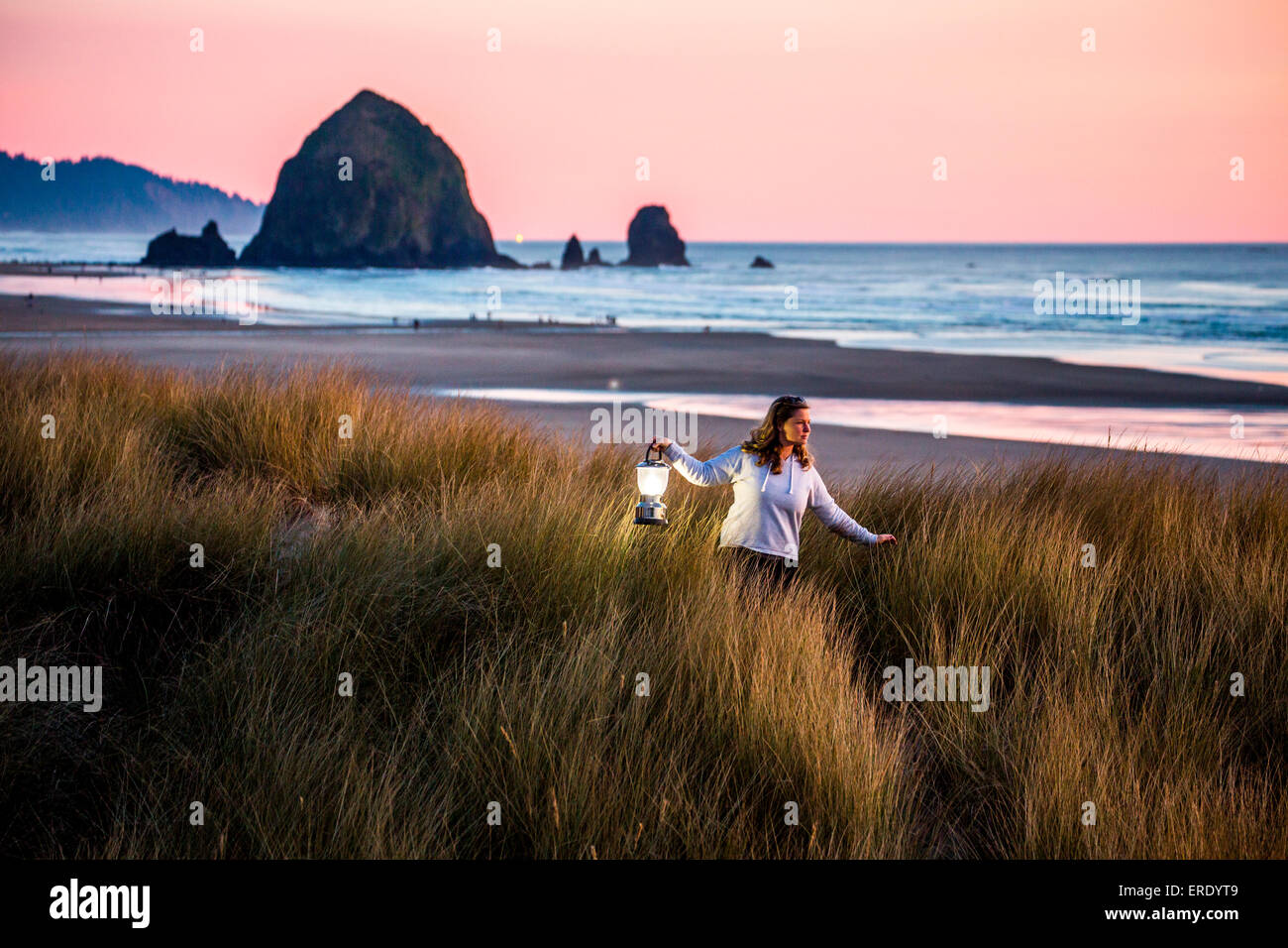 Kaukasische Frau, die die Laterne auf Cannon Beach, Oregon, Vereinigte Staaten Stockfoto
