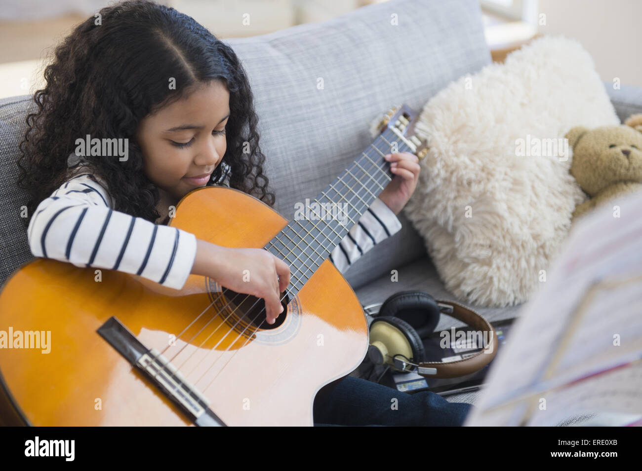 Gemischte Rassen Mädchen üben Gitarre auf sofa Stockfoto
