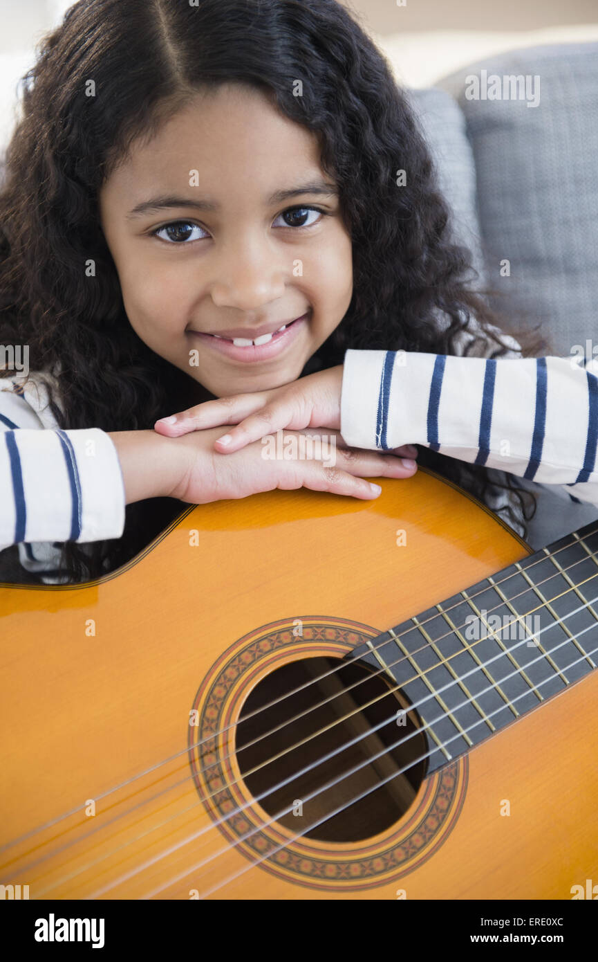 Gemischte Rassen Mädchen mit Gitarre auf sofa Stockfoto