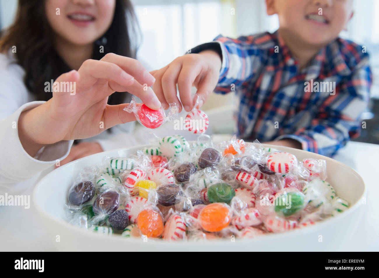Asiatische Bruder und Schwester Kommissionierung Süßigkeiten aus Schüssel Stockfoto