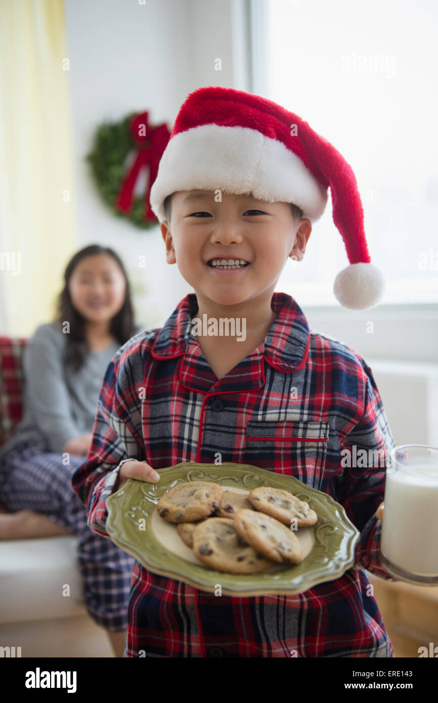 Asiatische junge hält Teller Kekse für den Weihnachtsmann Stockfoto