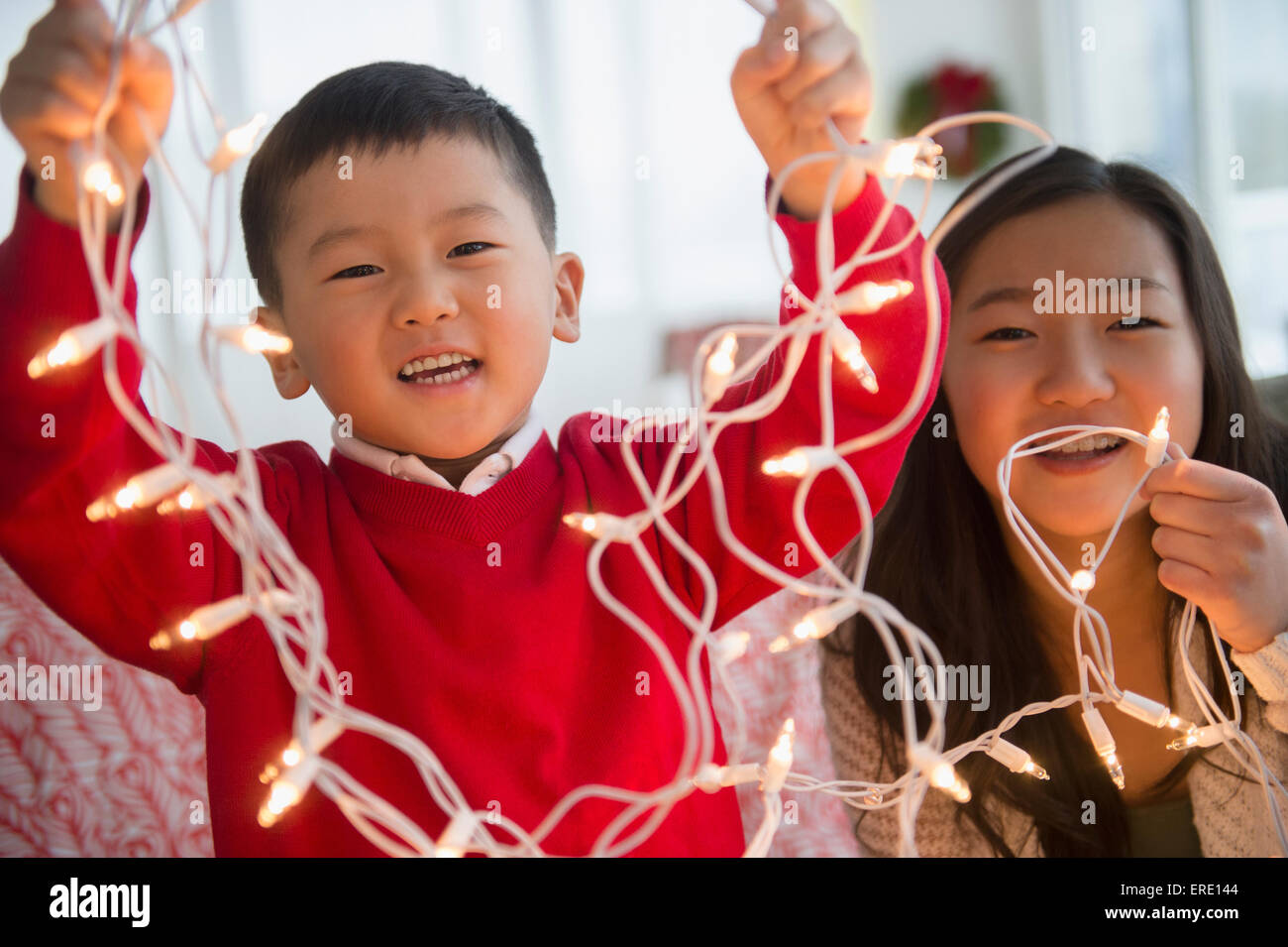Asiatische Kinder spielen mit Weihnachten Lichterkette Stockfoto
