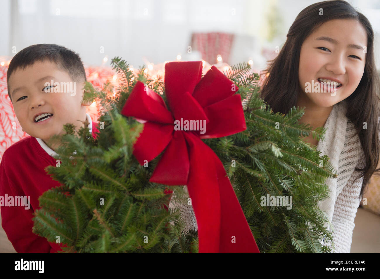 Asiatische Bruder und Schwester tragen Weihnachtskranz Stockfoto