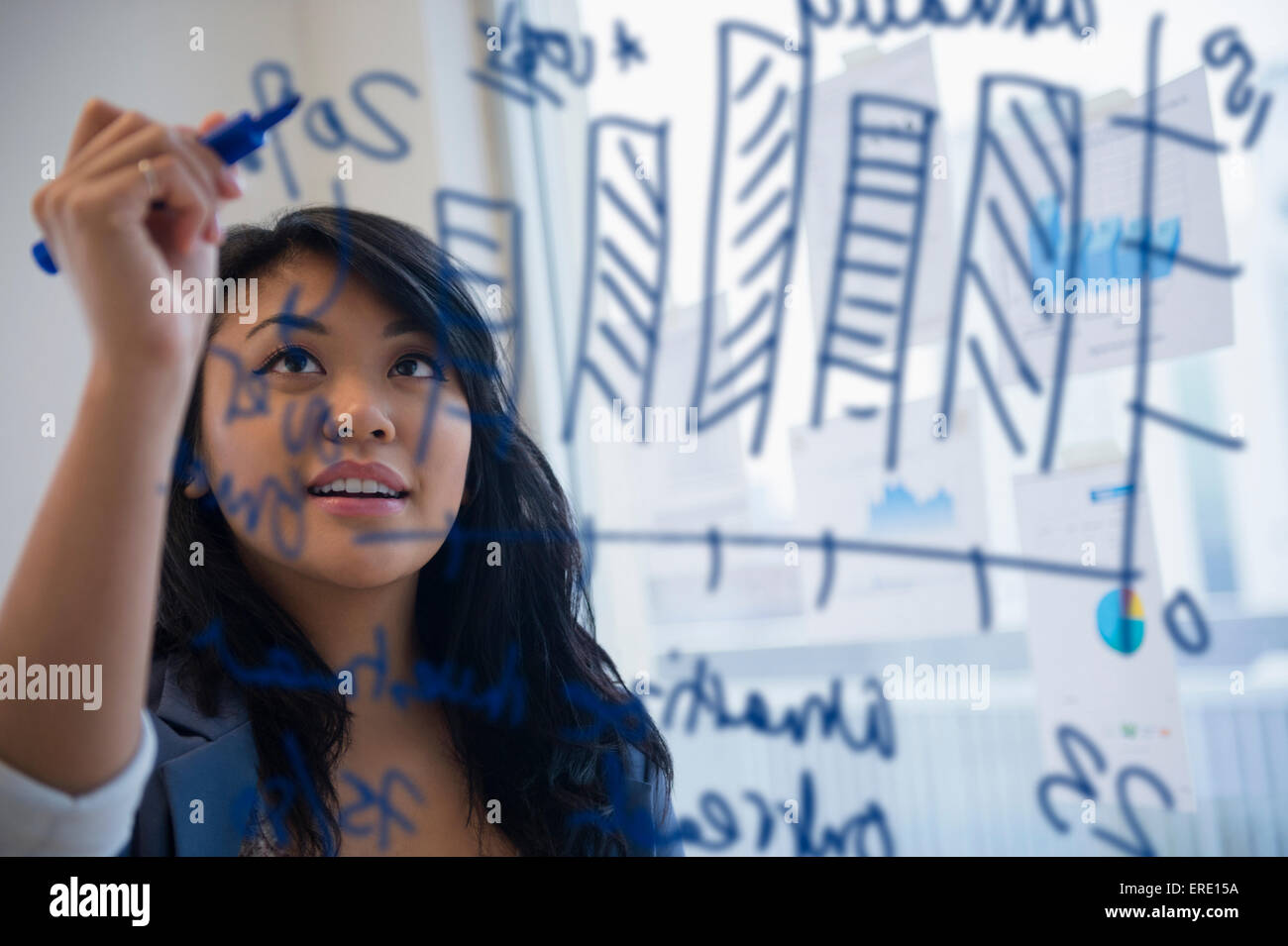 Pacific Islander Geschäftsfrau zeichnen Chart auf Glas im Büro Stockfoto