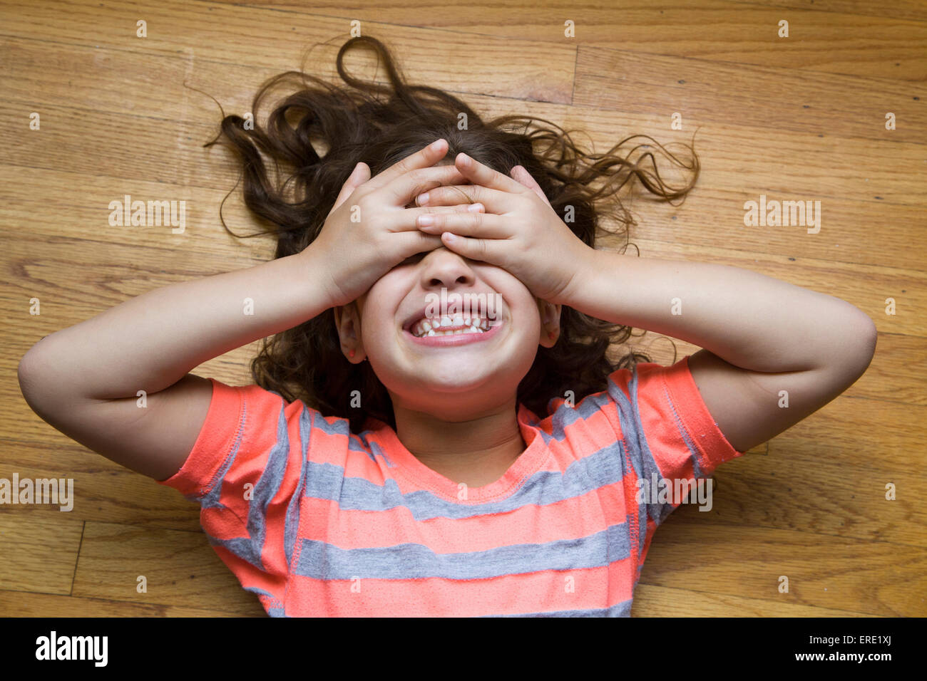 Lächelndes hispanischen Mädchen für ihre Augen am Boden Stockfoto
