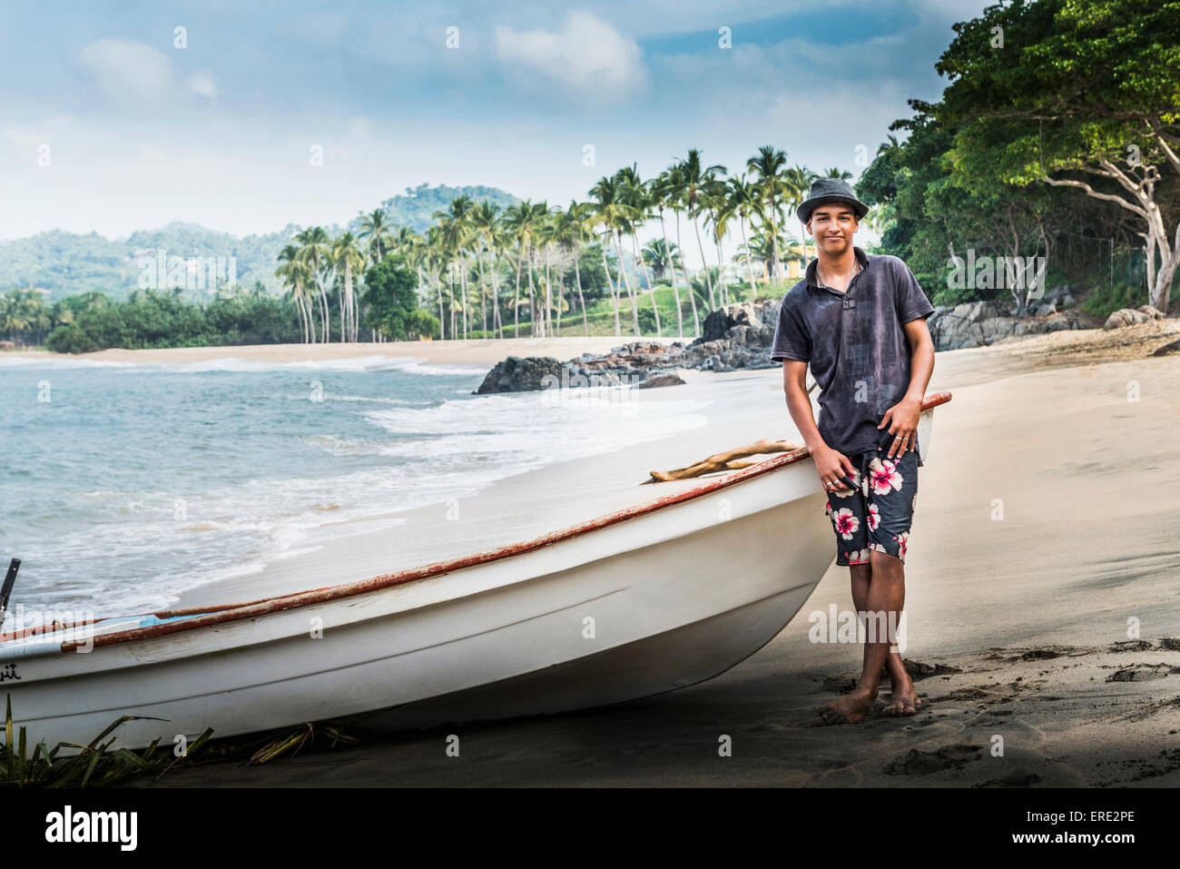 Hispanic Mann steht in der Nähe von Boot am Strand Stockfoto
