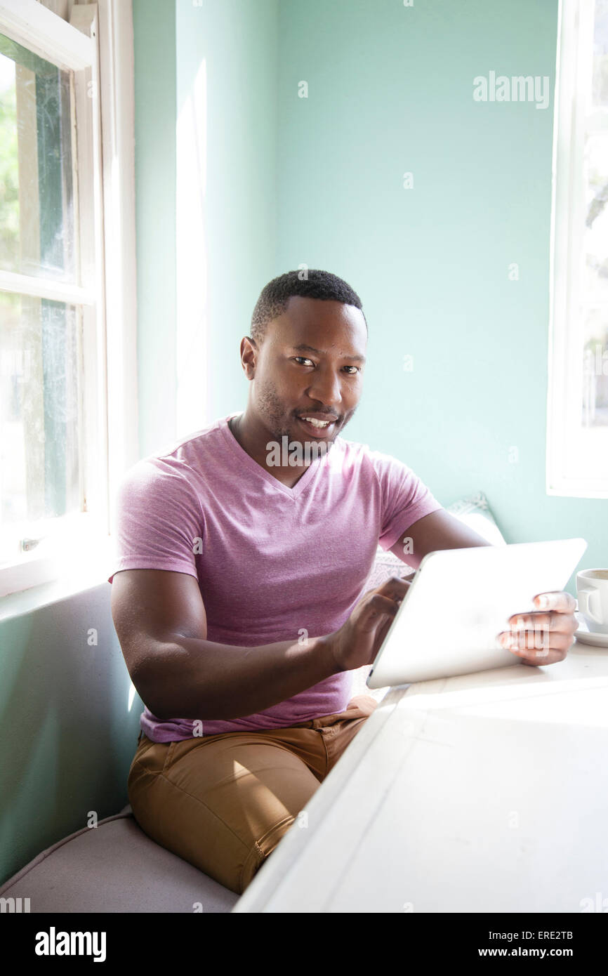 Schwarzer Mann mit digital-Tablette am Tisch Stockfoto