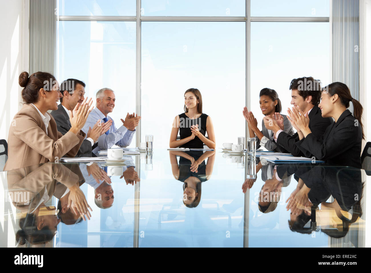 Gruppe von Geschäftsleuten mit Vorstandssitzung um Glastisch Stockfoto