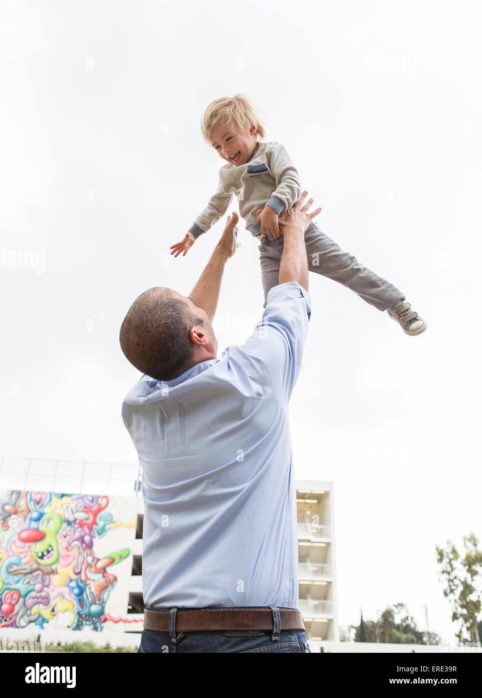 Hispanische Vater Sohn in Luft im Freien zu werfen Stockfoto