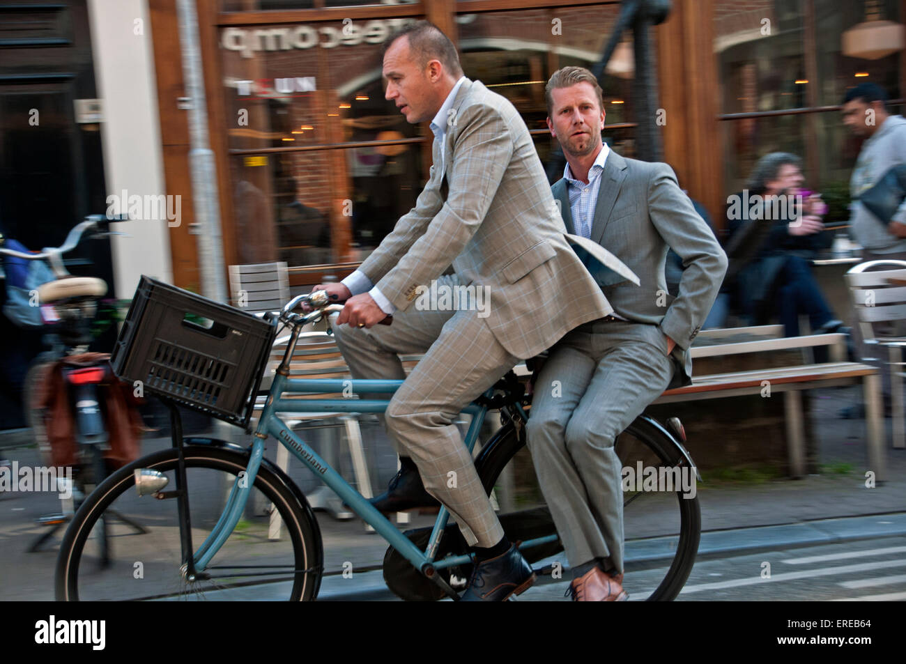 Zwei Männer in Anzügen Reiten zusammen auf dem Fahrrad in Amsterdam Stockfoto