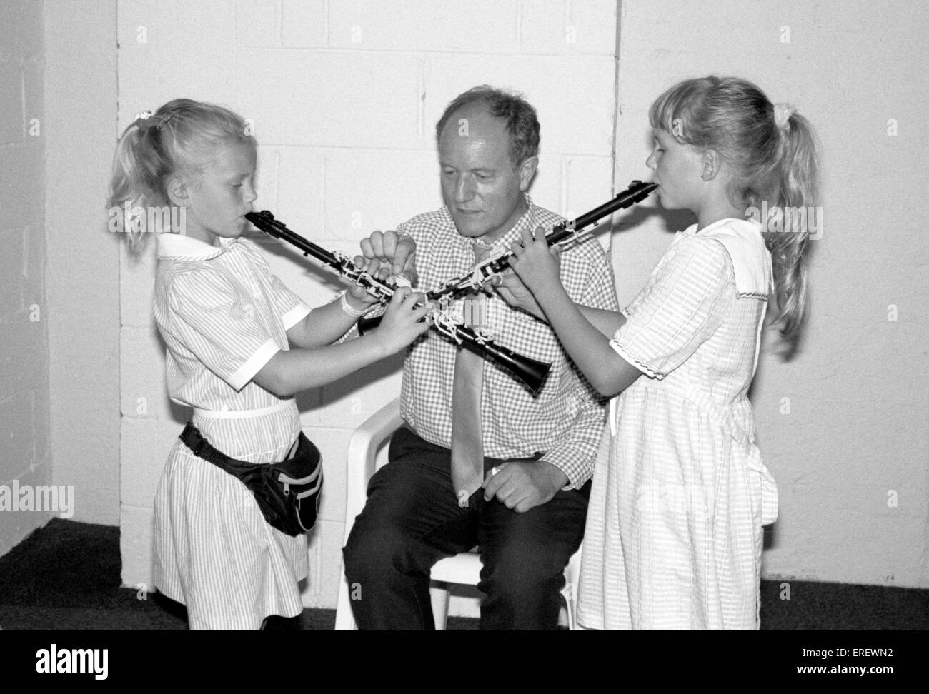 Ein Lehrer leitet zwei junge Mädchen auf der Klarinette am British Music Fair, Olympia, London. Stockfoto