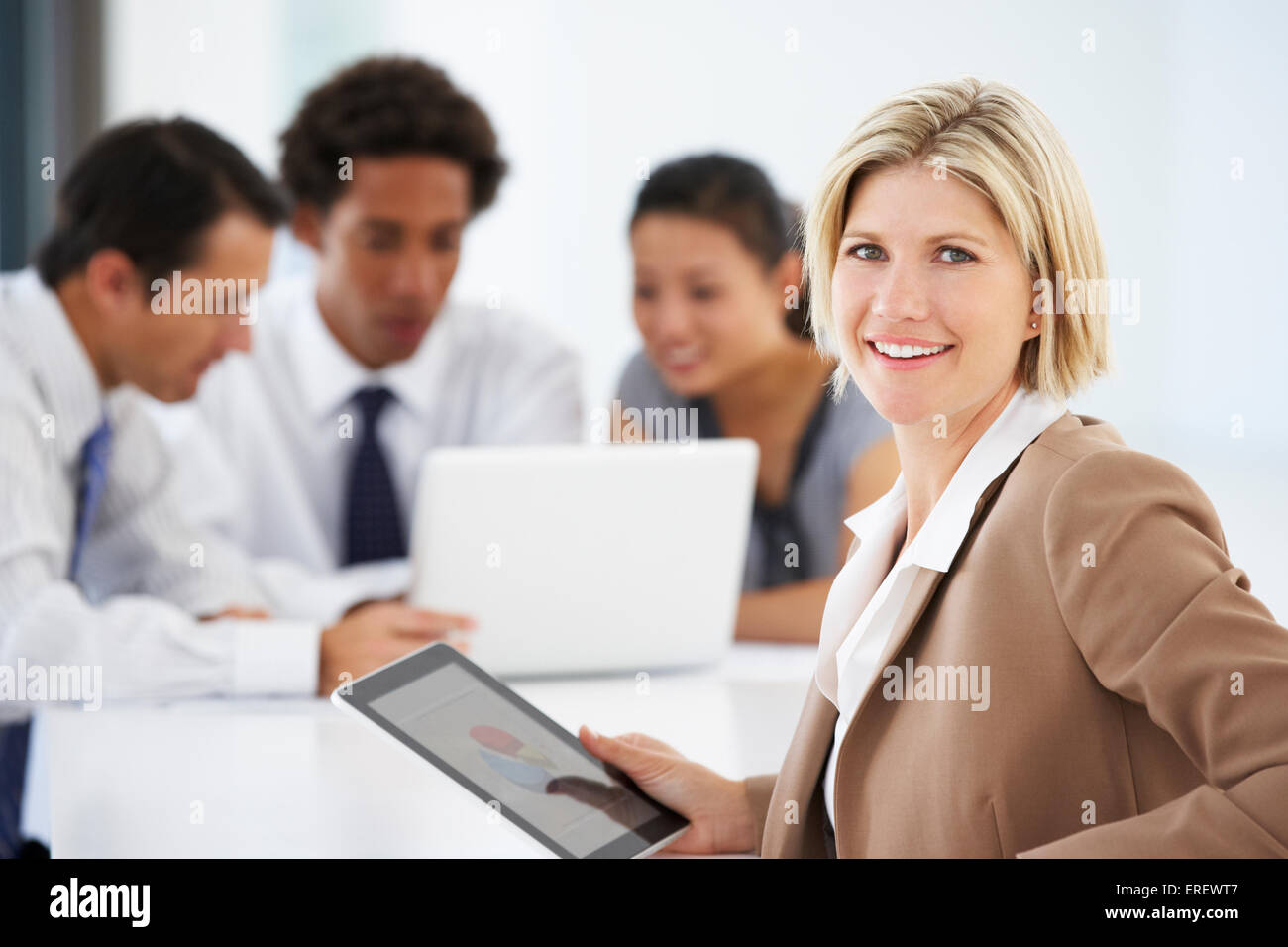 Porträt von weiblichen Executive mit Tablet-PC mit Office-Meeting im Hintergrund Stockfoto