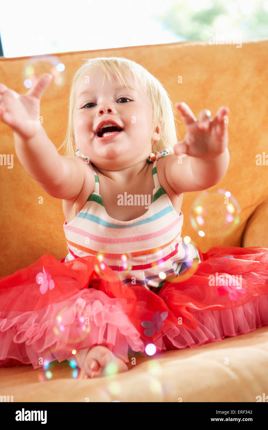 Junge Mädchen spielen mit Luftblasen auf Sofa Stockfoto