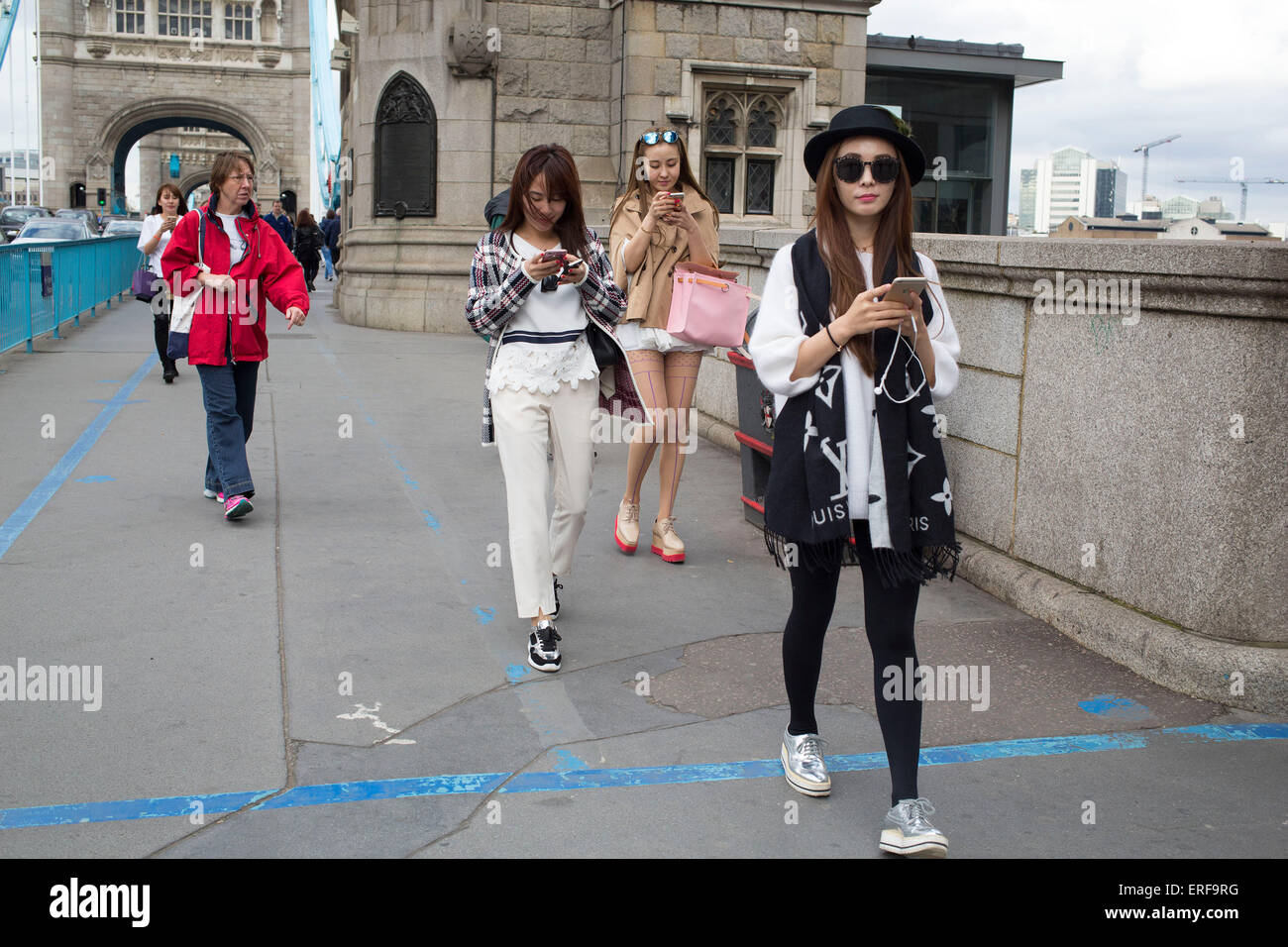 Drei chinesische Mädchen alle ihre Handys gleichzeitig zu verwenden. London, UK. Stockfoto