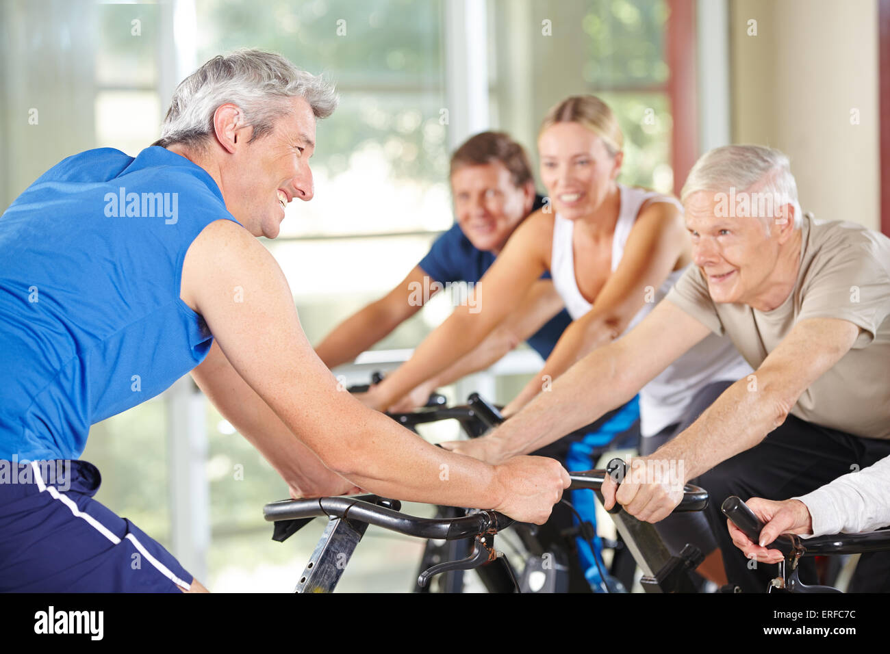 Senioren in der Spinnerei-Klasse mit Trainer in einem Fitnessstudio Stockfoto