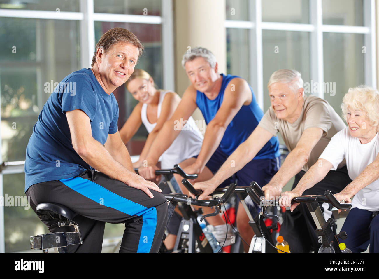 Der Mensch als Fitness-Trainer im Fitness-Studio trainieren mit hochrangigen Gruppe in der Spinnerei Klasse Stockfoto