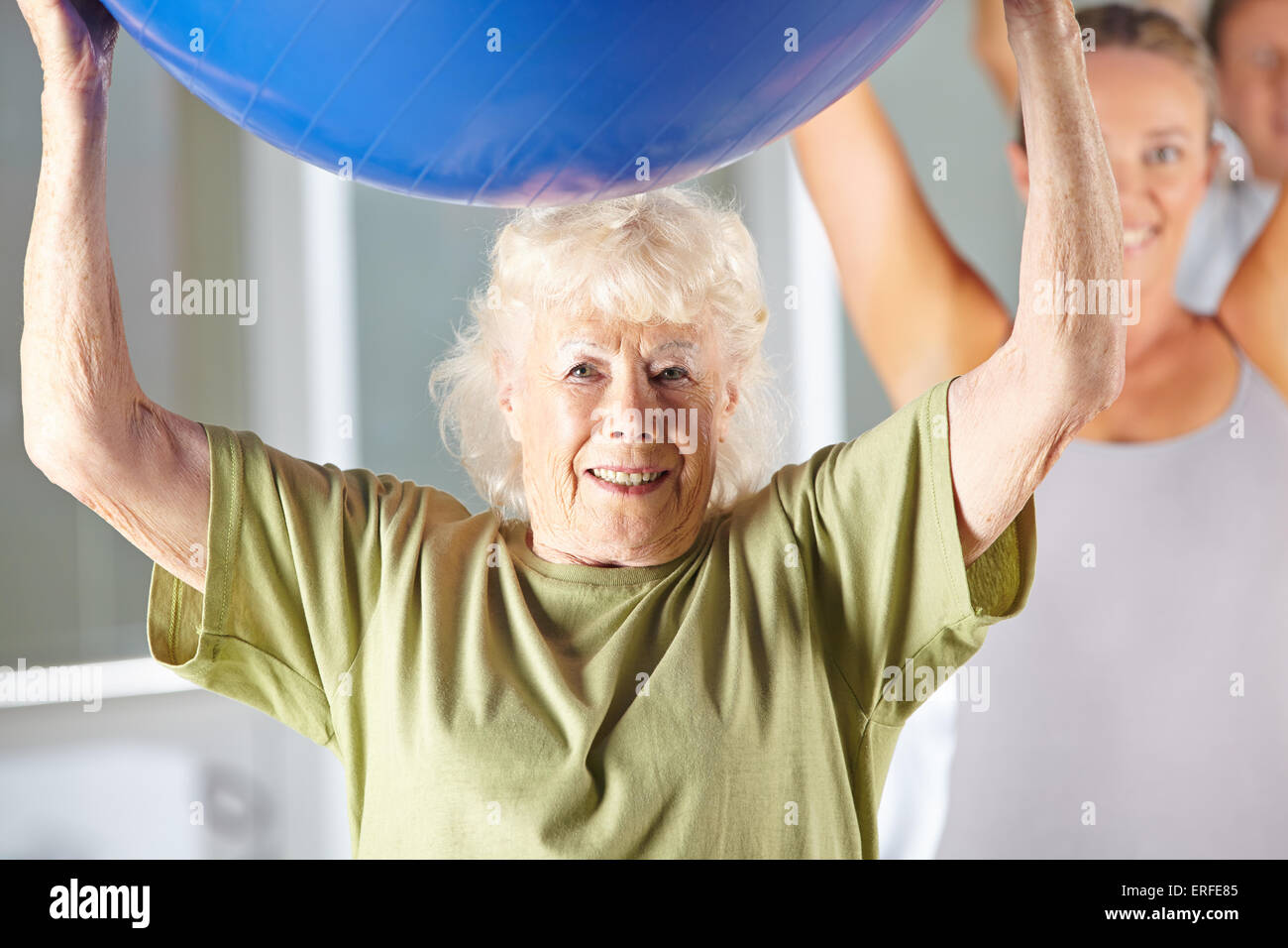 Alte Frau, die das Training mit Gymnastikball im Fitness-Center in der Reha Stockfoto