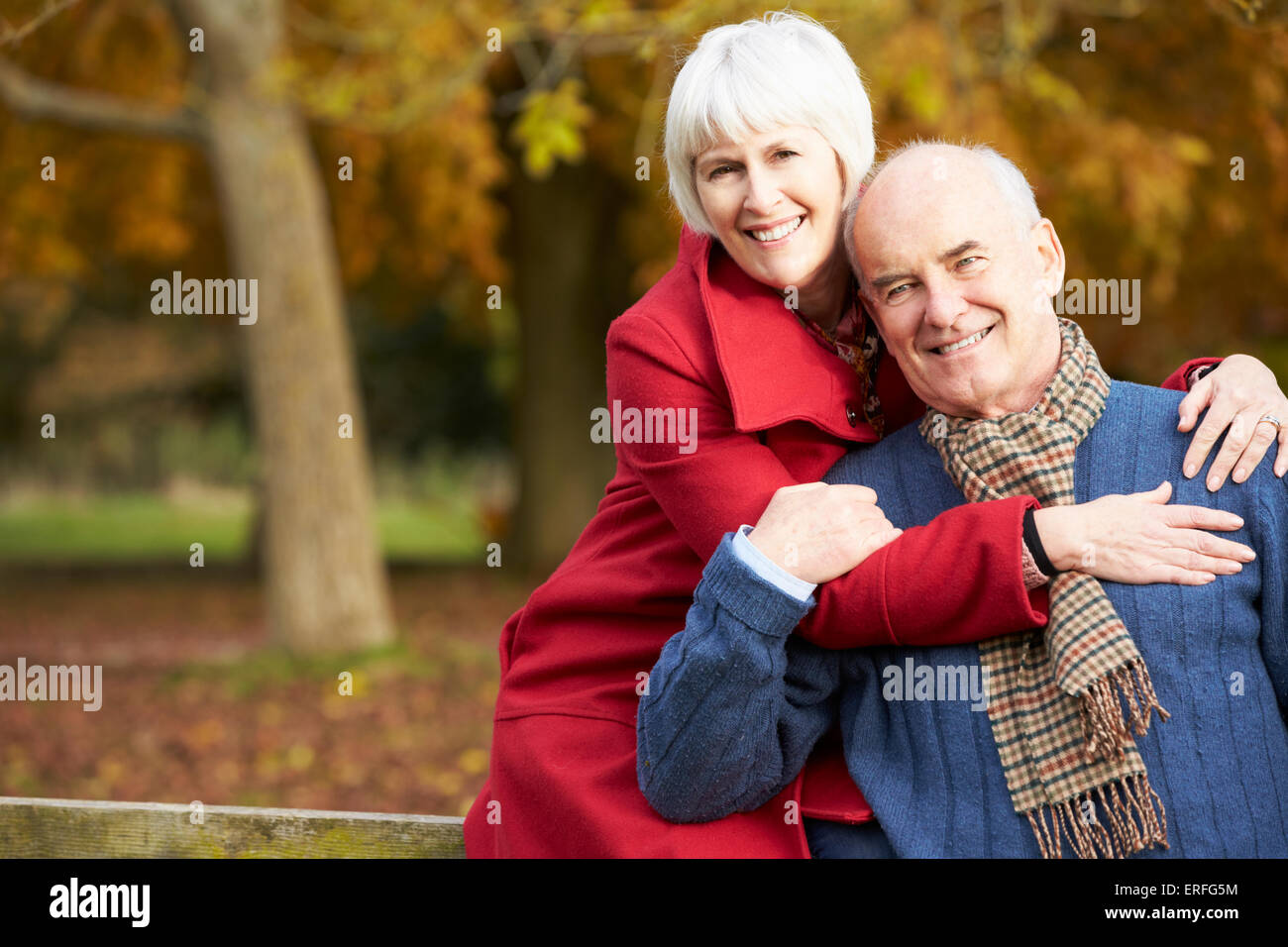 Romantische älteres Paar sitzt am Zaun im Herbst Wald Stockfoto