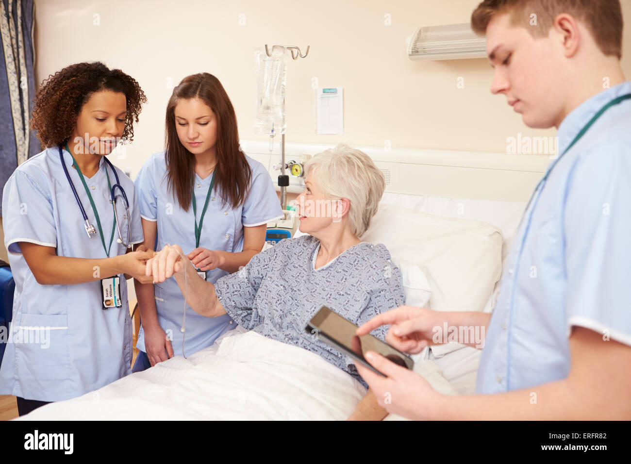 Azubi Pflegepersonal von weiblichen Patienten Bett im Krankenhaus Stockfoto