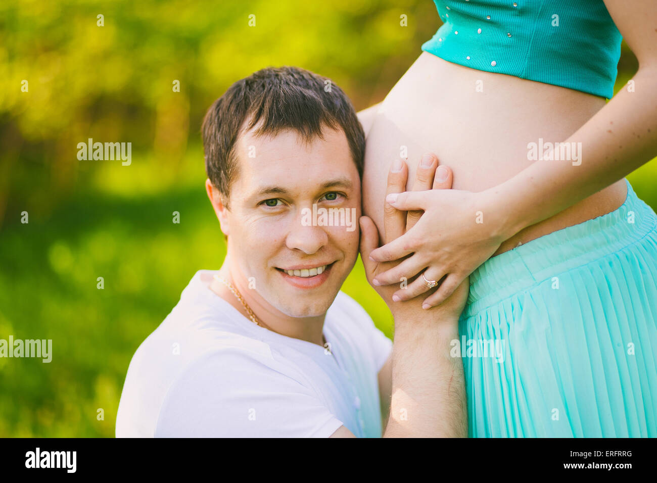 Porträt des Vaters mit Wange in der Nähe von schwangeren Bauch der Frau. Schwangere paar. Glückliche Schwangerschaft. Mann und Frau. Frau und Mann Stockfoto