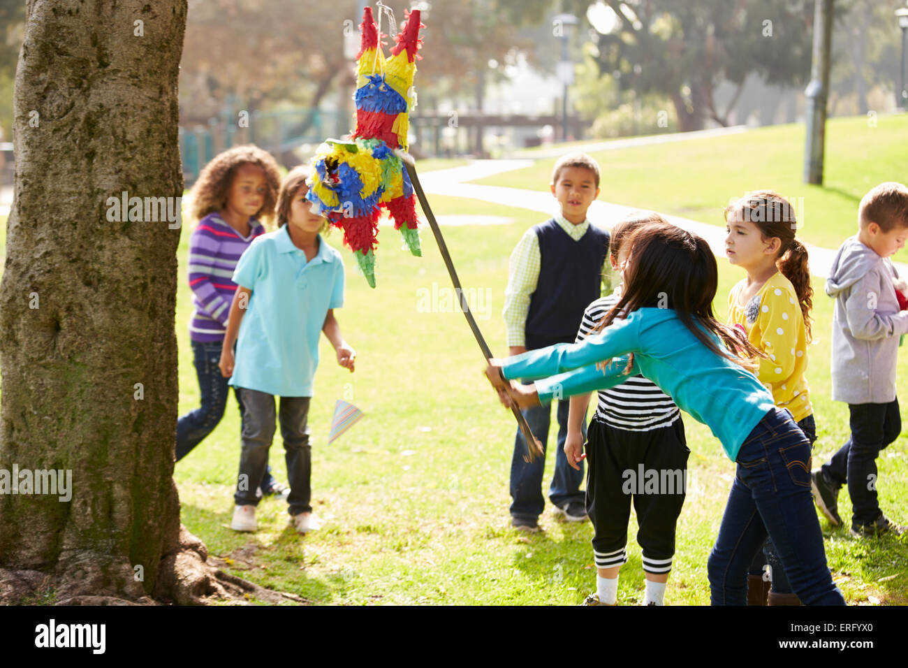 Kinder schlagen Pinata auf Geburtstagsparty Stockfoto
