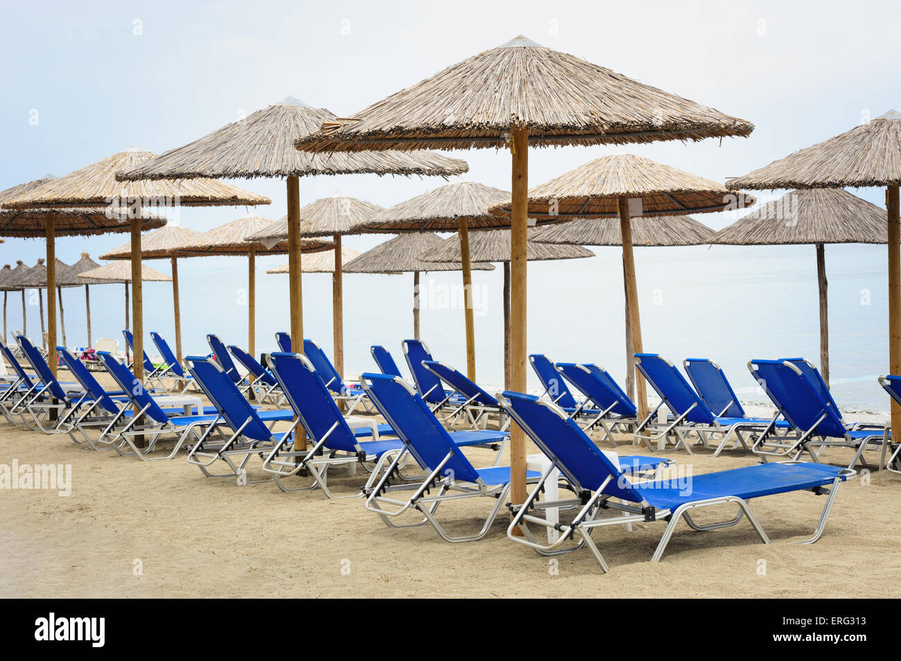 Reed-Sonnenschirme und Liegestühle am Strand Stockfoto