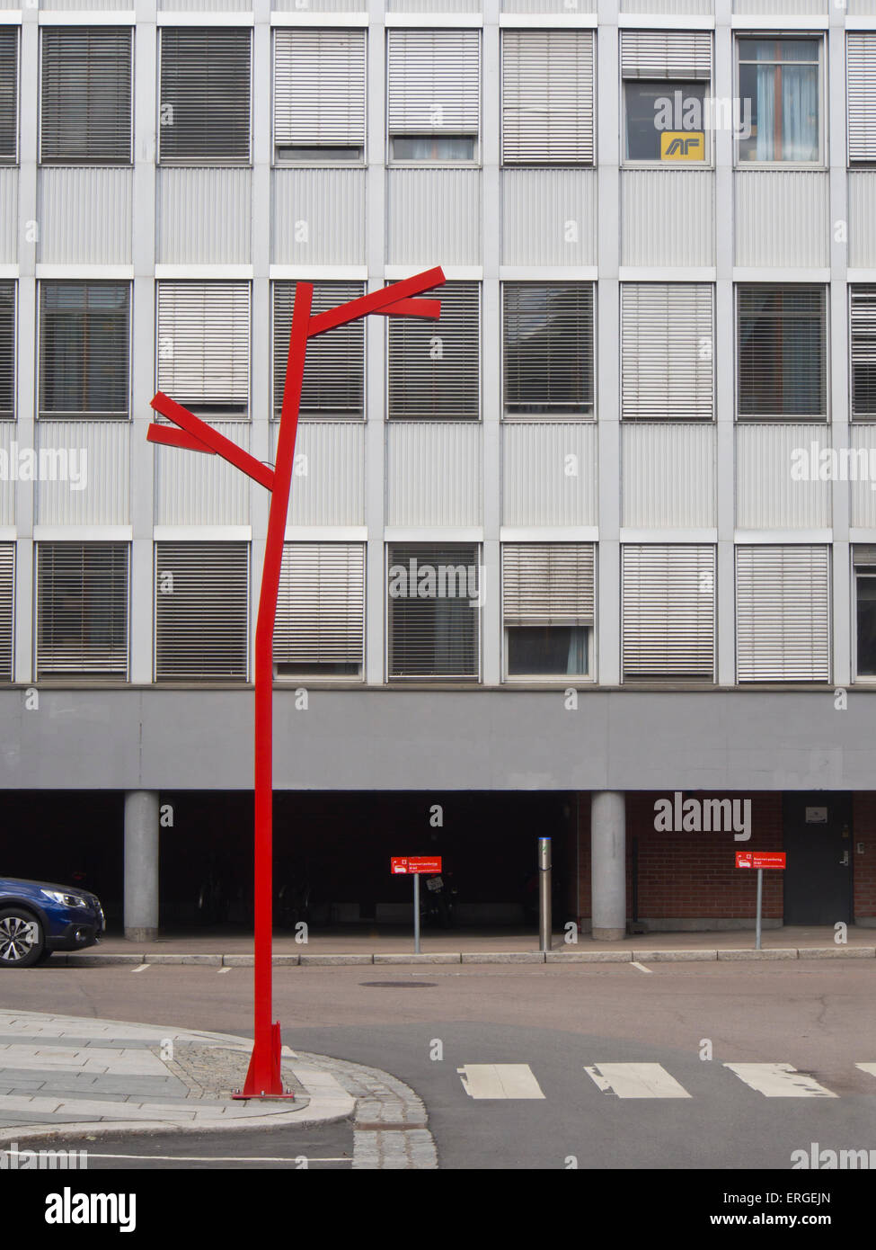 Einzelne rote lackiert Stahl Laterne in einem künstlerisch industriellen Stil gegen eine graue Bürogebäude in Kvaernerbyen, Oslo Norwegen Stockfoto