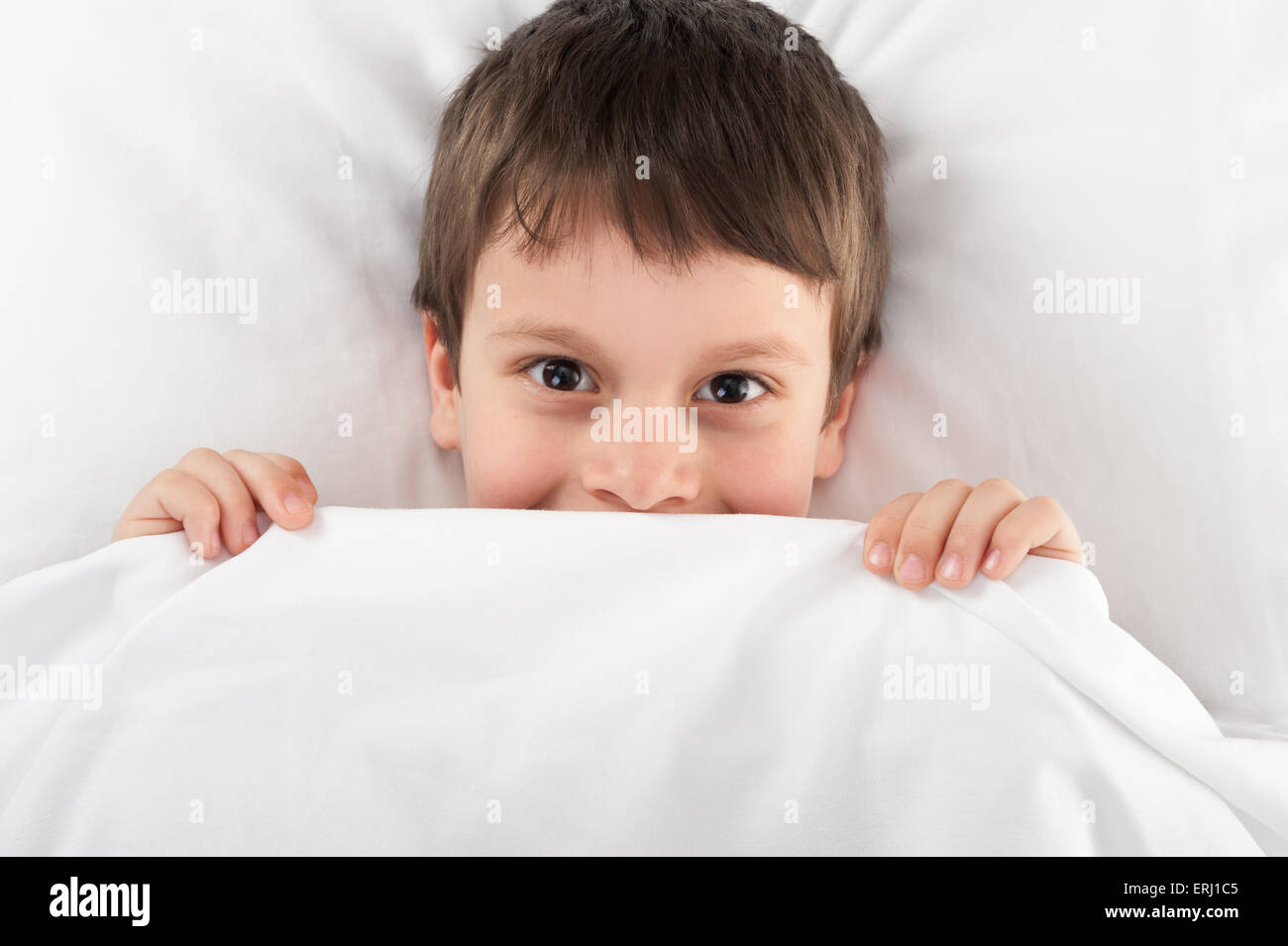 fröhliche junge versteckt unter der Decke Stockfoto