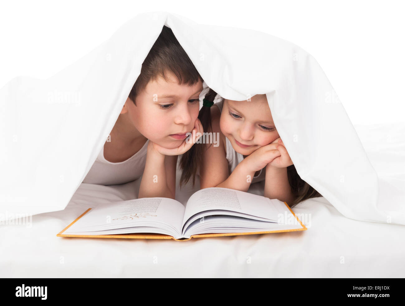 Kinder lesen ein Buch im Bett unter der Decke Stockfoto