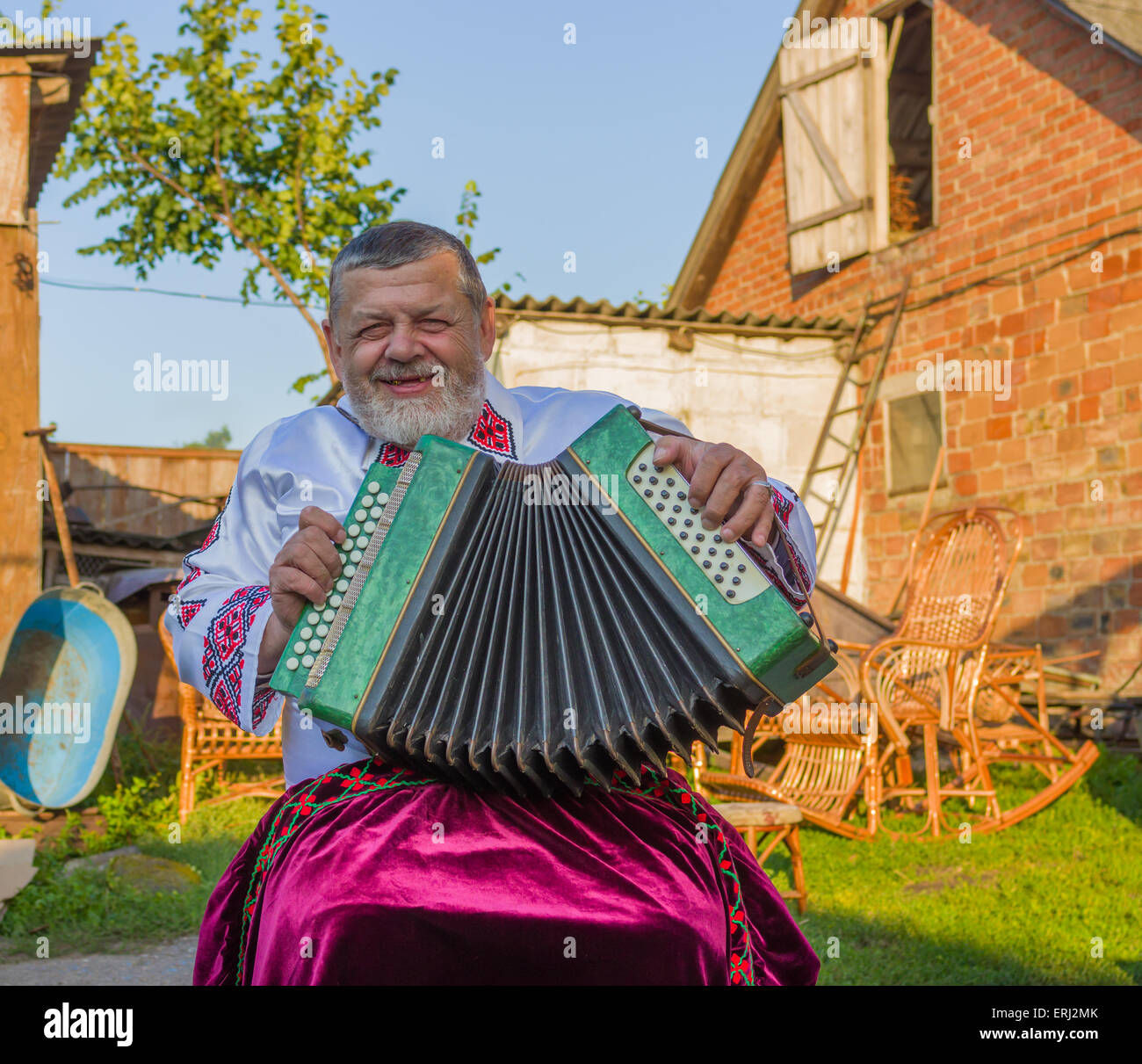 Ukrainische Land-Mann in traditioneller Kleidung spielen Knopfakkordeon Stockfoto