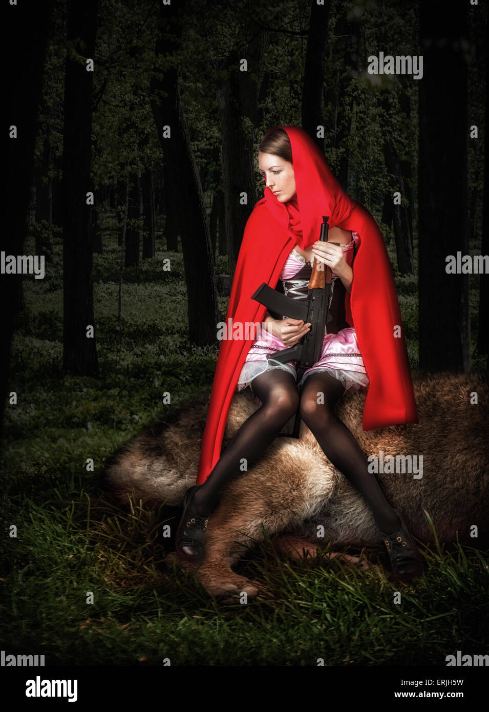 Mädchen Rotkäppchen mit automatischer im Holz sitzen auf getöteten wolf Stockfoto