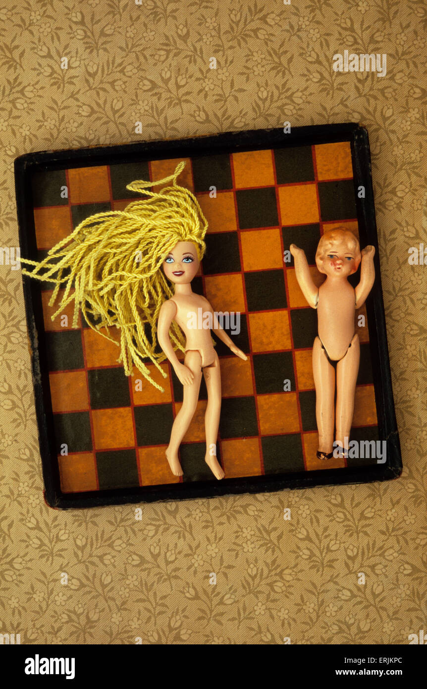 Kunststoff Mädchenpuppe mit strähnig gelbe Haare am Schachbrett mit Jahrgang Biskuit-Puppe mit den Armen in der Luft liegen Stockfoto