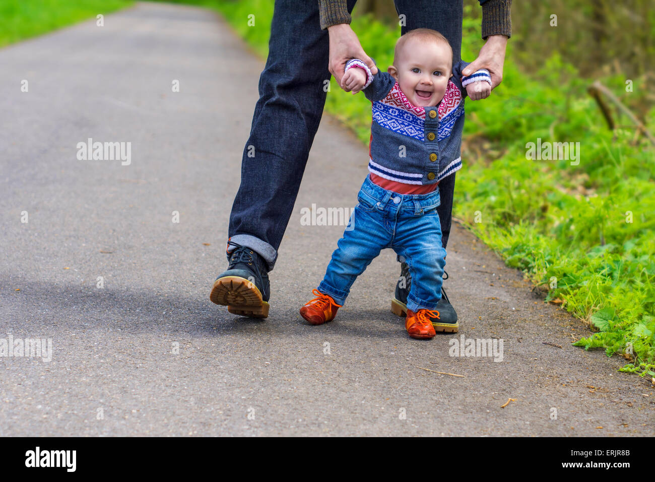 Vater sein Baby bei den ersten Schritten führen Stockfoto