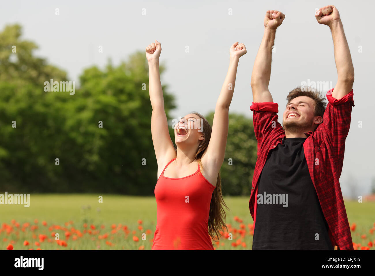 Euphorische glückliche Paar Arme in einem Land mit roten Blüten Stockfoto