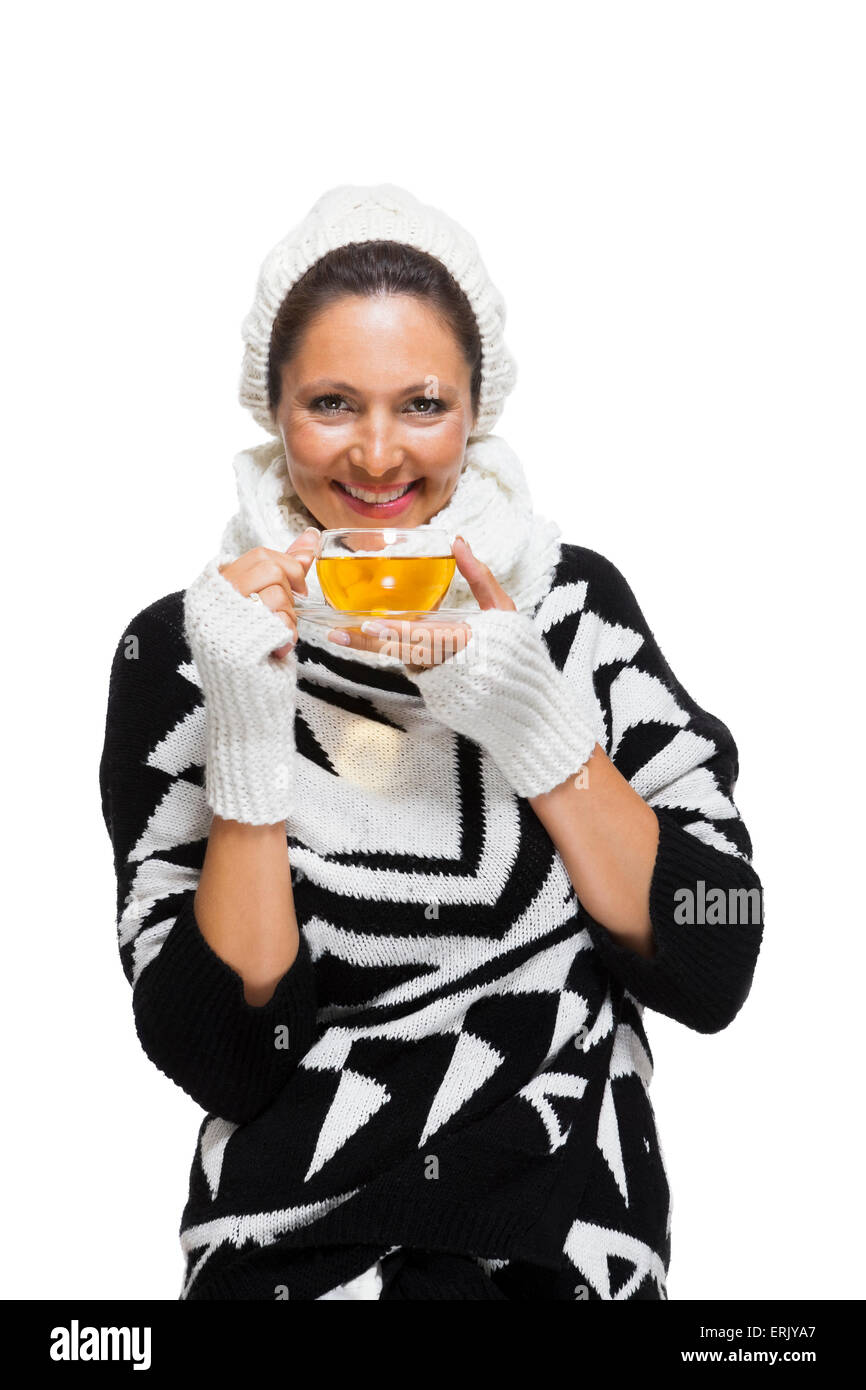 Kalten attraktive stilvolle Frau in einem eleganten schwarzen und weißen Winteroutfit umklammert eine Tasse heißen Kaffee in der Hand während des savori Stockfoto