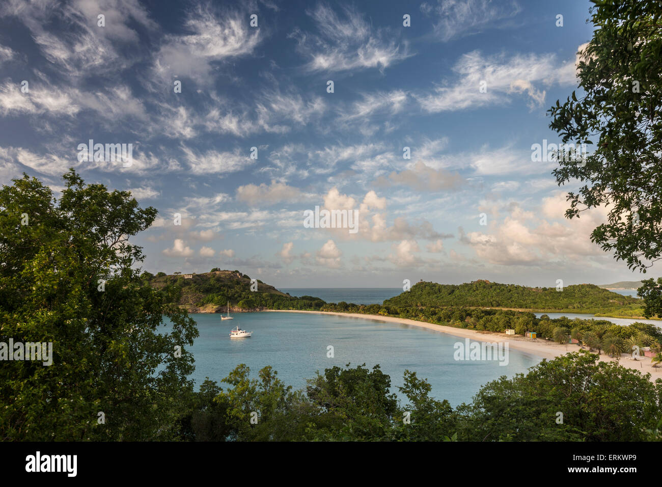 Die Wolken werden von der untergehenden Sonne auf Deep Bay eine Strecke von Sand, die von üppiger Vegetation, Antigua, Leeward-Inseln versteckt beleuchtet. Stockfoto